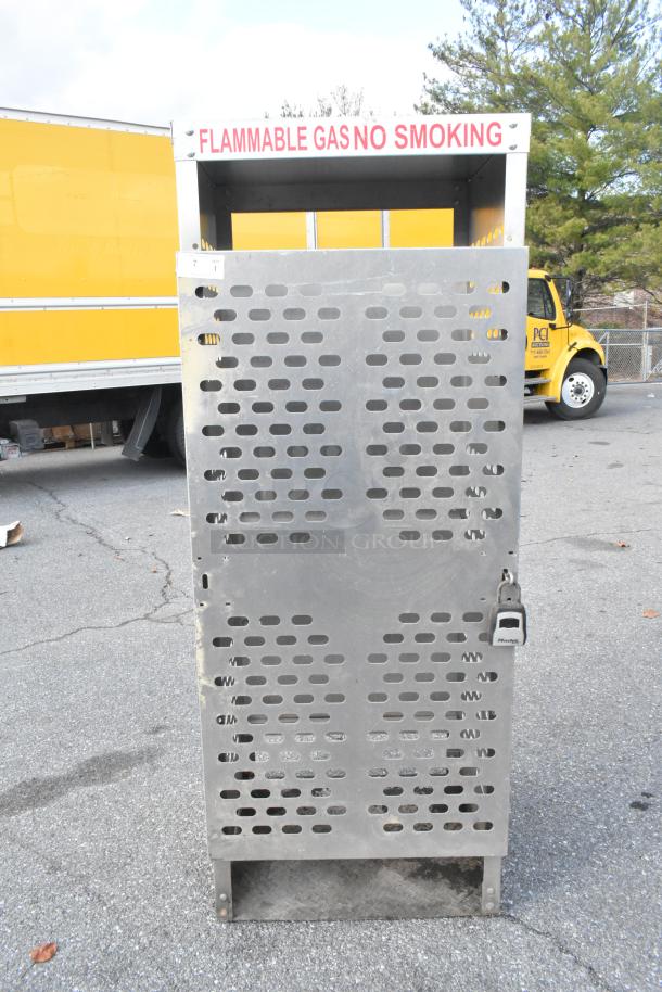 American Standard Mfg metal propane tank cage with ventilation slots, locking mechanism, and "Flammable Gas No Smoking" label.