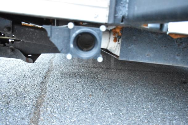 Close-up view of the underside of a 2021 Nationwide 24' unbranded cold food and beverage trailer, showing the exhaust outlet.