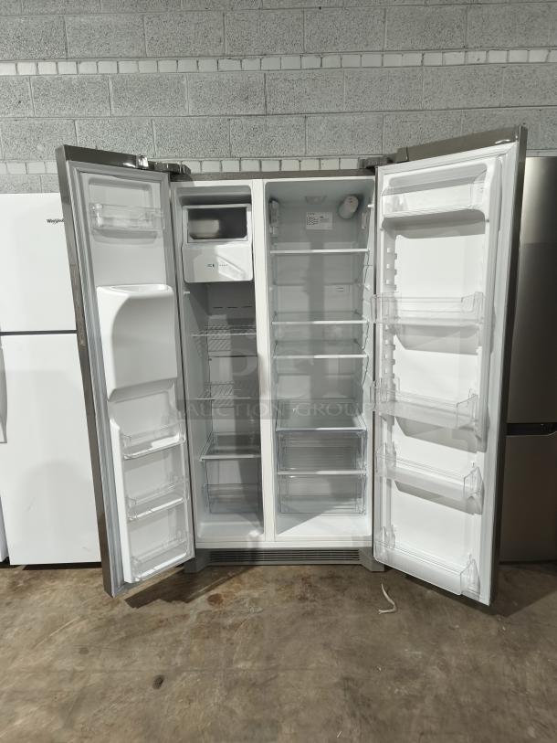 Frigidaire model FRSS26L3AFE, 25.6 cu ft side-by-side refrigerator, like new condition, open doors showing shelves and bins.