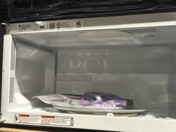 Brand new GE over-the-range microwave, model JVM6175SK6SS, 1.6 cu ft, minor cosmetic dents, interior view, tags visible.