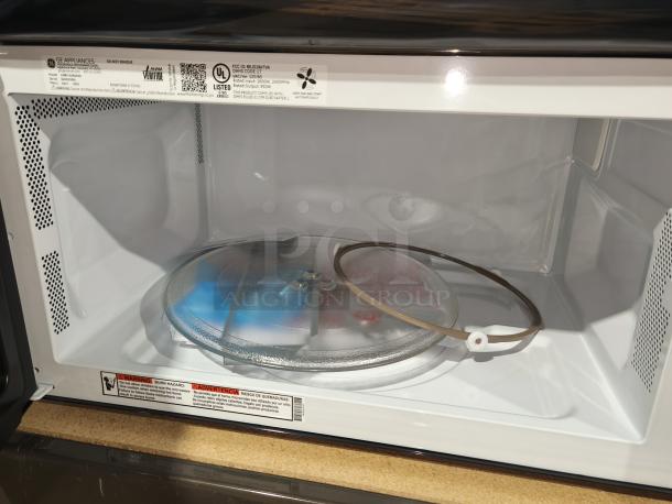 BRAND NEW SCRATCH AND DENT GE 1.6 cu ft over-the-range microwave oven, model JVM3162RJSS, interior view showing turntable and label details.