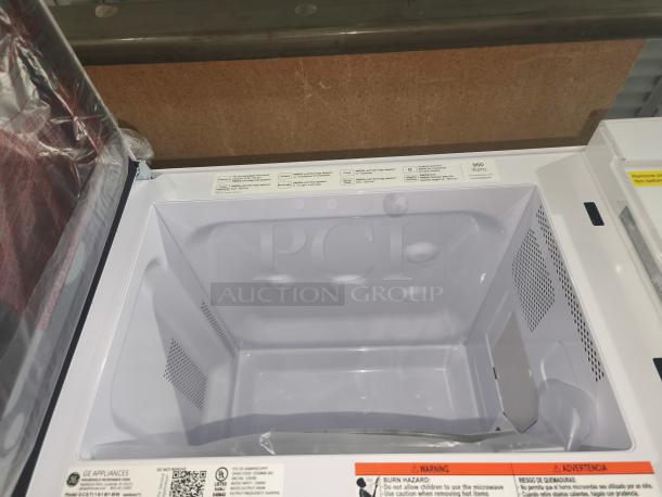 Brand new GE GCST11N1WWW 1.1 cu. ft. countertop microwave oven; minor scratches; 950 watts; visible warning labels.