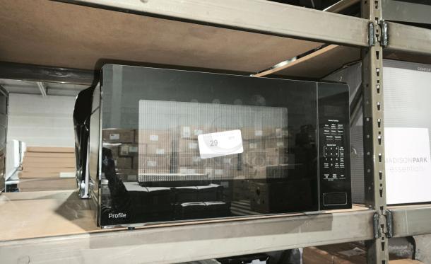 BRAND NEW GE Profile 2.2 Cu. Ft. Sensor Microwave, Model PCWK22U1WBB, on shelf with minor scratches.