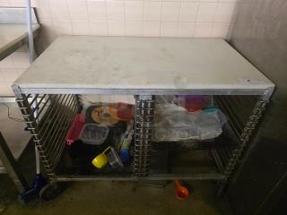 Bun Rack Mobile Work Table with Wire Pan Slides, used condition, visible surface wear, includes lower storage for kitchen items.