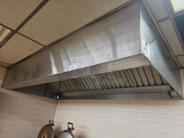 Stainless steel commercial exhaust hood, mounted, with visible vent filters. Slight wear, label on side indicating model details.