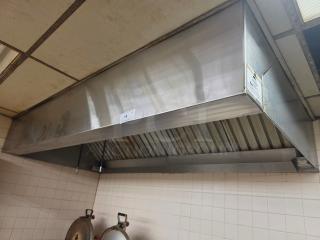 Stainless steel commercial exhaust hood, mounted, with visible vent filters. Slight wear, label on side indicating model details.