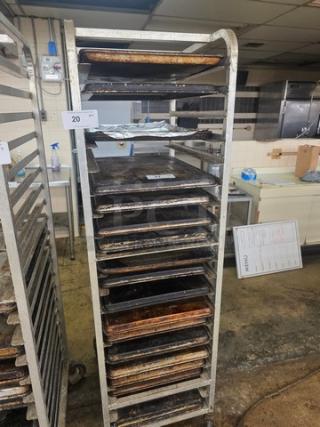 Sheet pan rack on casters with multiple shelves, holding various baking trays. Signs of wear and use visible.