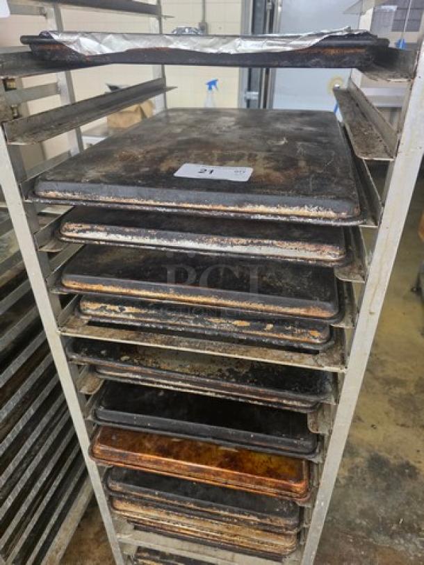 Lot of 20 full-size sheet pans on a rack, showing signs of wear. Rack not included. Tag reads "21".
