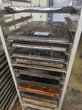 Lot of 20 full-size sheet pans on a rack, showing signs of wear. Rack not included. Tag reads "21".