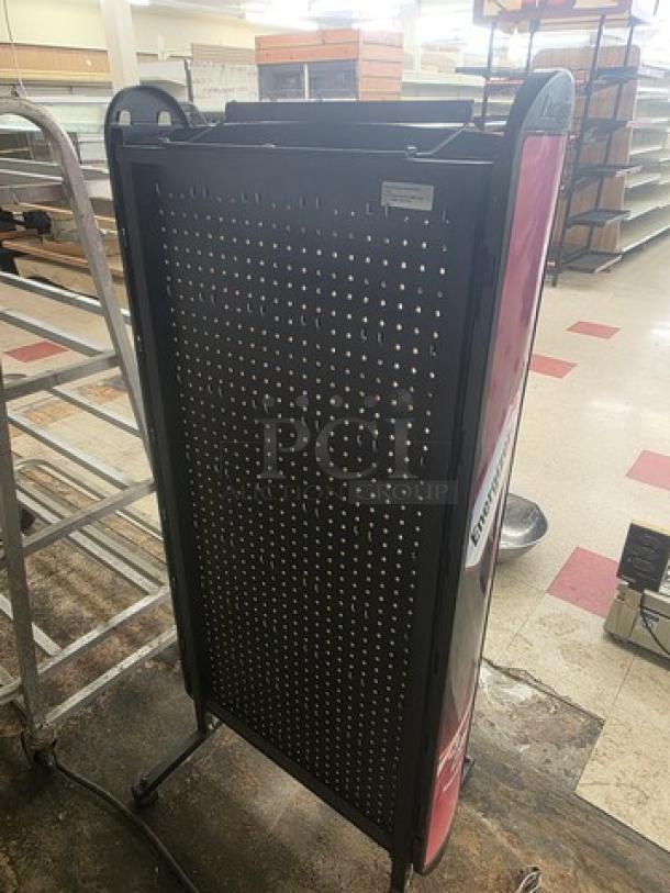 Black metal display rack with perforated panel, used condition. Features side panels, sturdy wheels, and adjustable shelves.