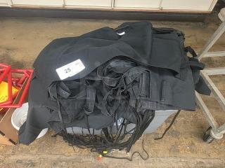 A stack of black kitchen aprons; label indicates a lot of 25 aprons. Aprons appear in good condition, featuring ties and neck loops.