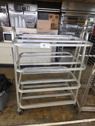 Industrial Lug Dolly, metal frame, four-tier design, on caster wheels. Condition: used, with visible wear. Tag labeled "26".