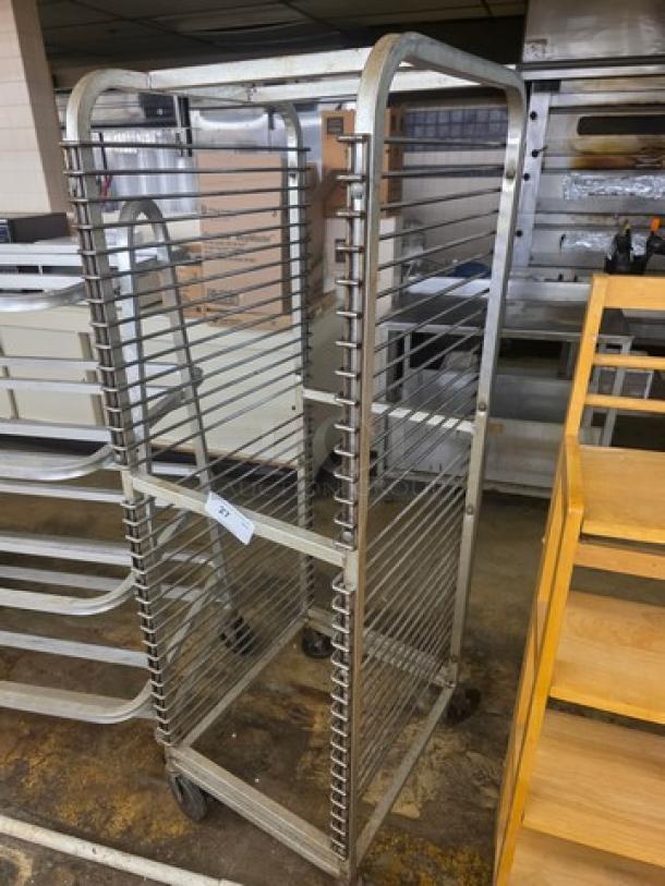 Nesting bun pan rack with casters, metal construction, multiple slots for pans, shows minimal wear, includes inspection tag.