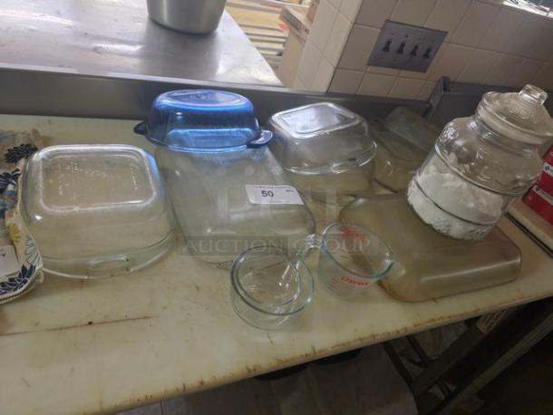 Lot of miscellaneous glass containers including Pyrex measuring cups, square baking dishes, and a large jar. Good condition.