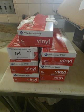 One lot of Fleetwood Model 1412 disposable gloves, size XL, in red "Prime Source" boxes, stacked on a table.