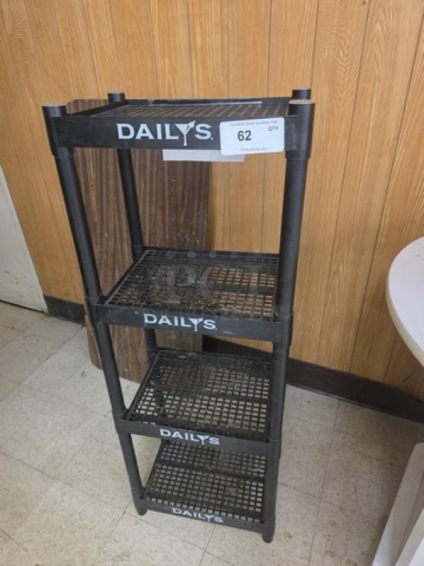 Four-tiered plastic shelving unit with "DAILY'S" branding, black color, used condition, tag labeled "62 QTY".