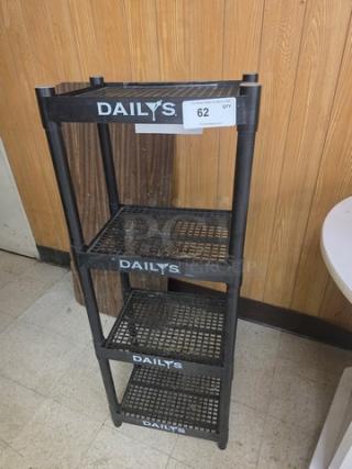 Four-tiered plastic shelving unit with "DAILY'S" branding, black color, used condition, tag labeled "62 QTY".