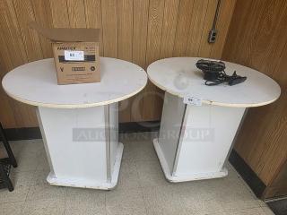 Lot of 2 white round pedestal tables, used condition. Numbered labels "63" and "64" visible. Contents on tables not included.