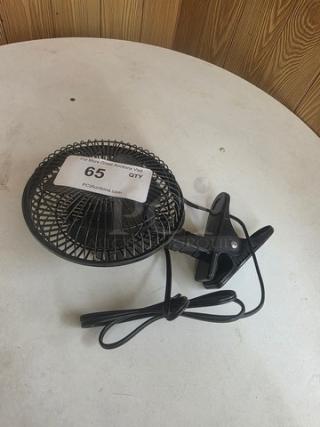 Black small clip-on fan with a protective grille, power cord, and visible auction label numbered 65, in used condition.