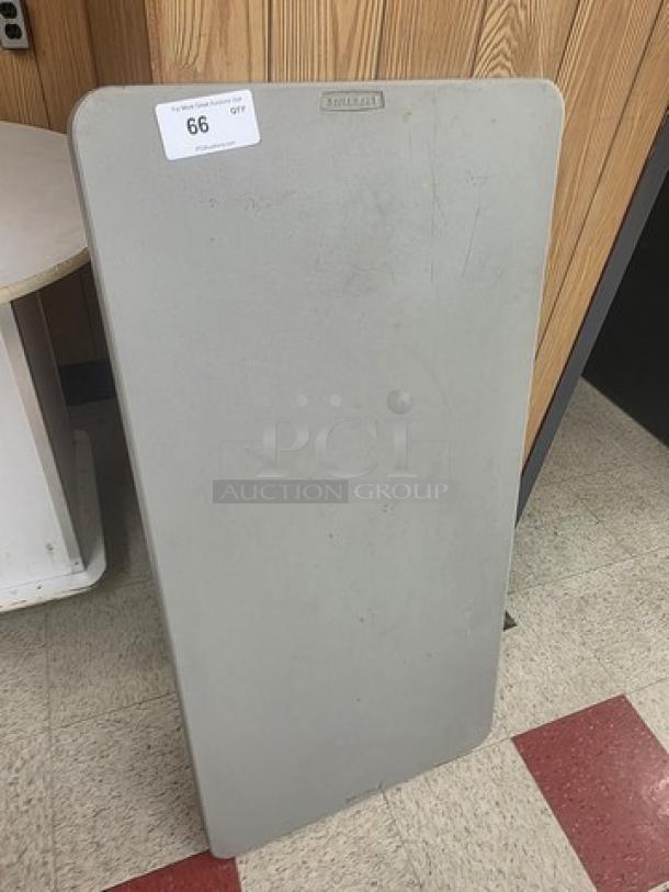 Foldable table with rectangular shape, gray surface. Visible label with number 66. Slight wear, suitable for events or small spaces.