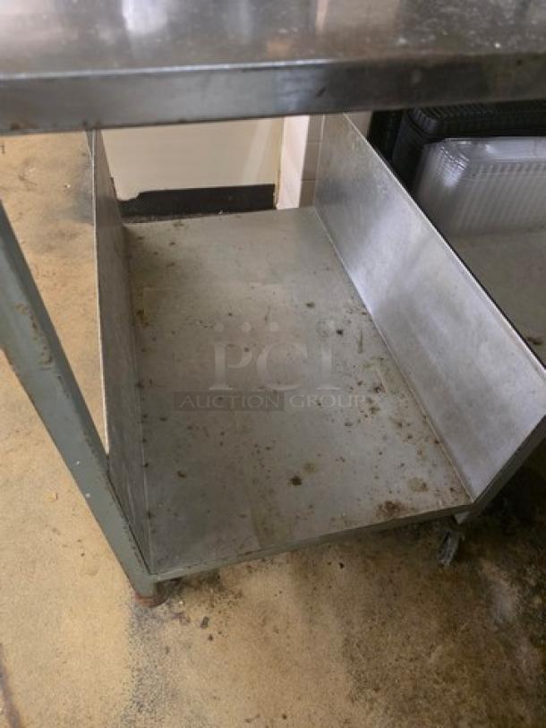 Stainless steel cart with two shelves, showing signs of wear and stains. Durable construction, suitable for versatile use.