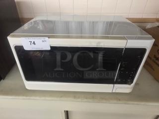 White countertop microwave with digital controls, minor wear. Auction tag 74. Visible on counter setting.