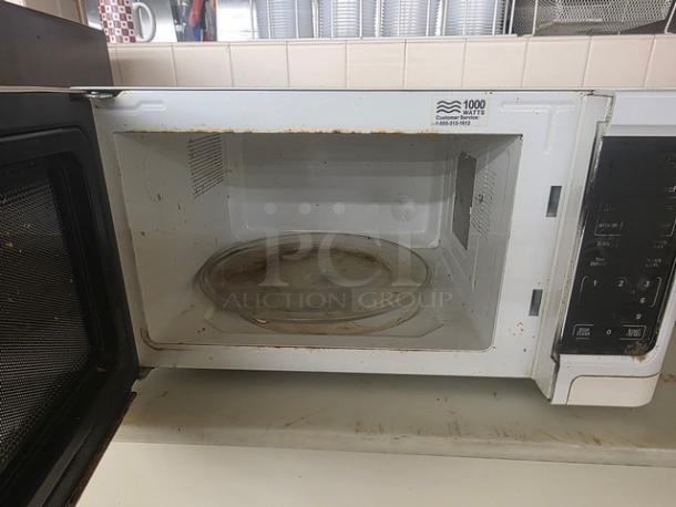Old microwave with a 1000-watt capacity, visible rust and stains, and a control panel with multiple settings. Interior includes a glass turntable.