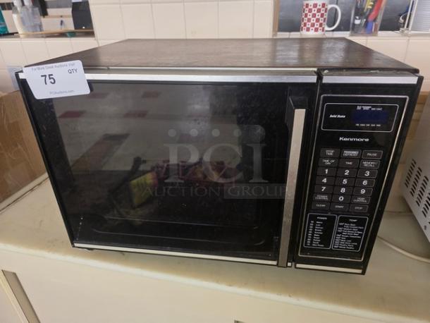 Kenmore microwave with digital keypad, black and stainless steel finish. Visible wear and auction tag labeled "75".