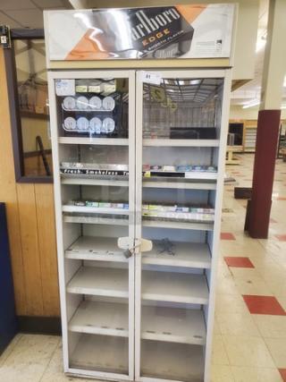 Glass-front cigarette display case with Marlboro Edge branding. Multiple shelves, lockable doors, some tobacco products visible. Good condition.