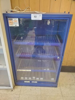 Blue, glass-door display case with three wire shelves. Minor wear visible on the glass and frame. Tag indicates auction lot 82.