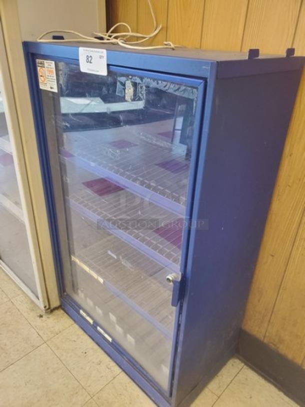 Blue glass-door display case with three shelves, lockable handle, good condition. Number 82 tag on top, visible scratches.