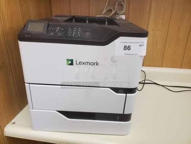Lexmark MS725 Monochrome Laser Printer, gently used. Features digital display, keypad, two paper trays, and auction label.