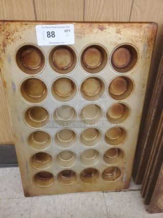 Lot of 2 muffin/cupcake baking pans, each with 24 cups. Visible wear and rust; tag reads “For More Great Auctions Visit,” lot number 88.
