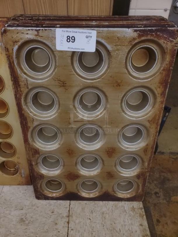 Lot of 8 muffin/cupcake baking pans with 12 slots each. Used condition, visible wear. Auction label indicates item number 89.