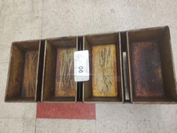Lot of five 4-compartment loaf pans, showing signs of wear and patina; numbered tag "06" visible.