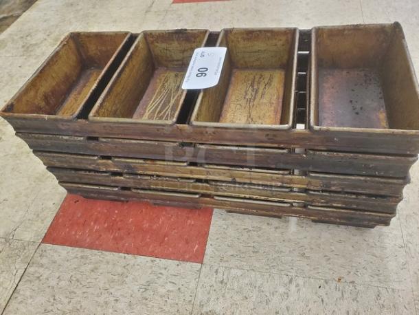 Lot of five 4-compartment loaf pans, used condition, stacked. Tag indicates "90, Qty 5, (5XBID)."