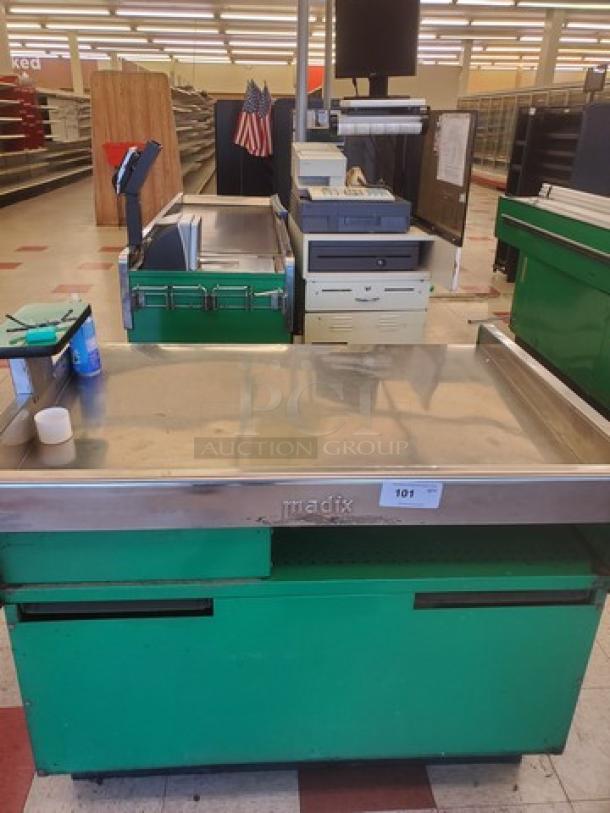 Supermarket checkout counter with green base, stainless steel top, and integrated conveyor belt. Madix brand, in used condition.