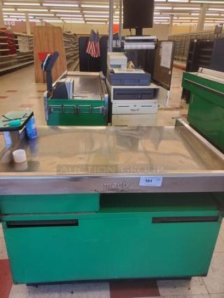 Supermarket checkout counter with green base, stainless steel top, and integrated conveyor belt. Madix brand, in used condition.