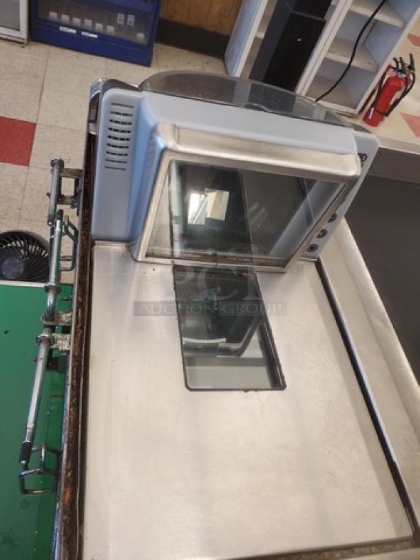 Supermarket checkout counter with integrated scanner, metallic finish, used condition. Features conveyer belt and display screen.