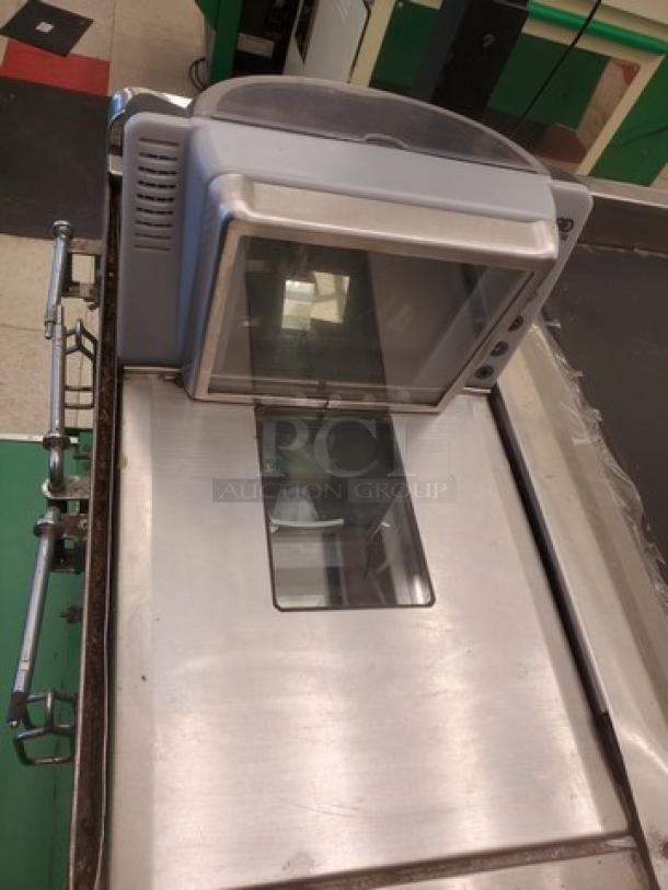 Supermarket checkout counter with integrated scanner, metal surface, and side rail. Used condition, suitable for retail use.