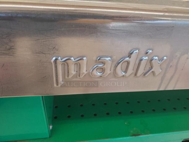 Stainless steel supermarket checkout counter by Madix, featuring a durable surface with visible wear, showcasing brand name.