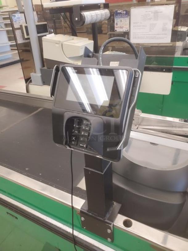 Supermarket checkout counter with conveyor belt, card payment terminal, and green-paneled sides. Suitable for retail settings.