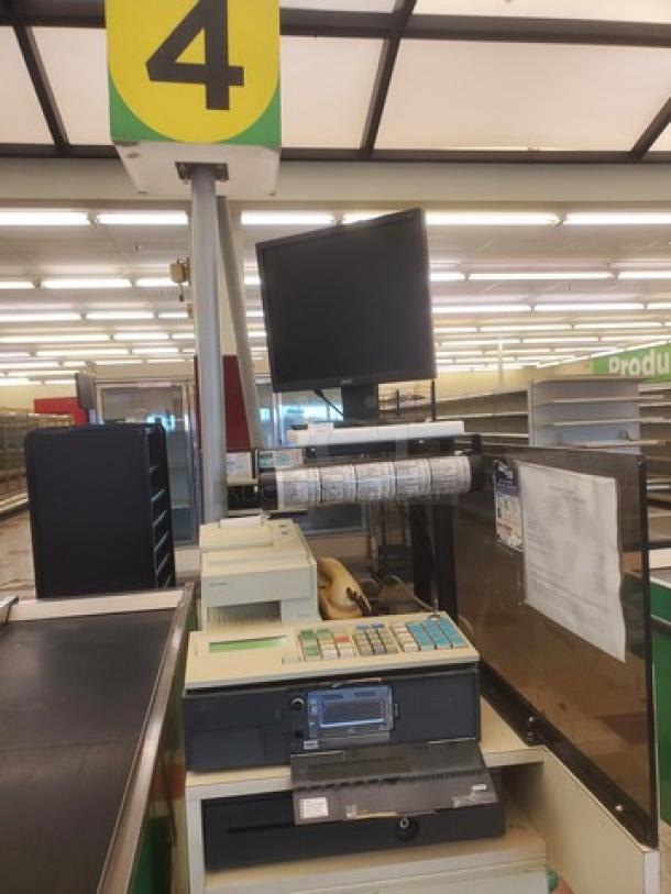 Supermarket checkout counter with monitor, keyboard, cash register, conveyor belt; features lane number 4 sign, used condition.