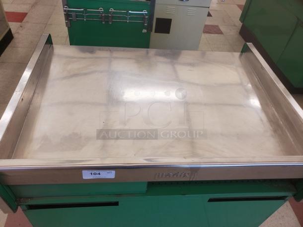Stainless steel supermarket checkout counter with green base, fair condition, engraved "medix" logo, visible item tag labeled "104".