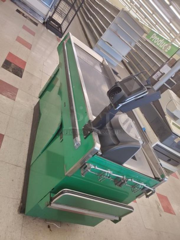 Green supermarket checkout counter with scanner and bagging area, metal trim, and storage compartments. Good condition.