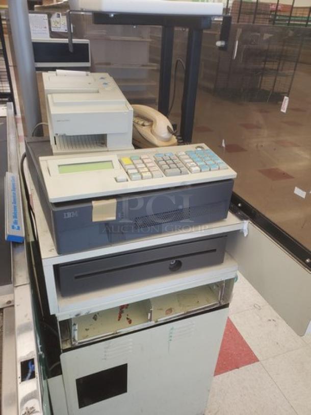 Supermarket checkout counter with IBM register, receipt printer, and cash drawer, in used condition.
