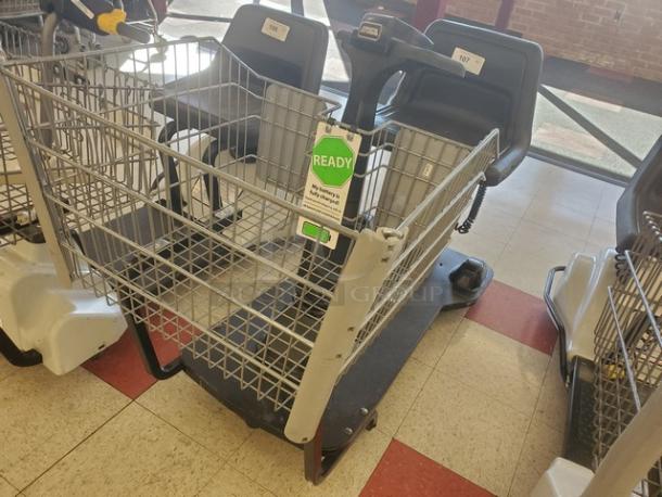 Motorized shopping cart with gray metal frame and attached seat. Green "READY" tag indicates operational condition.