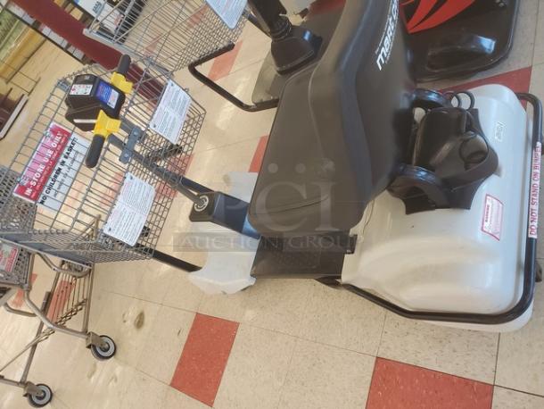 Motorized shopping cart with a black seat, steering handle, and attached metal basket. Features control panel with labels. Used condition.