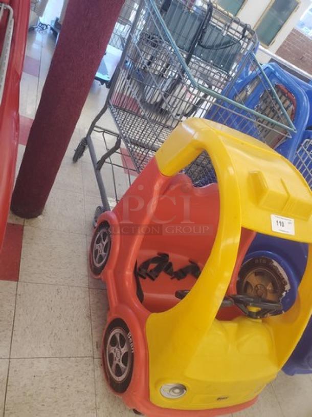 Brightly colored cartoon car shopping cart with steering wheel and seats, lightly used condition, fun and functional for children.