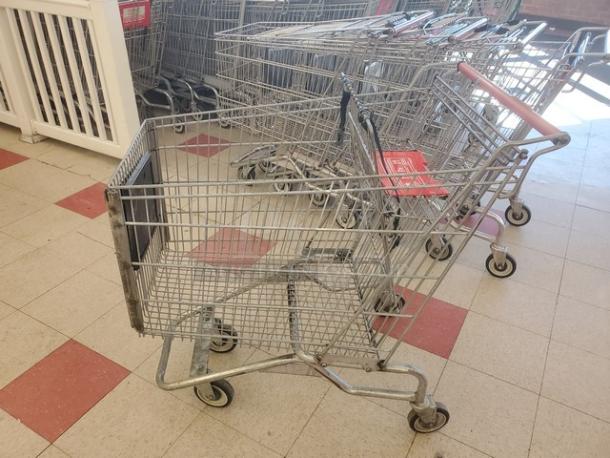 Lot of 5 metal shopping carts in used condition. Features red handles and sturdy wheels. Ideal for retail use.
